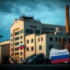 A modern industrial complex with prominent Soviet-era factory architecture featuring the 'Tula Machine Building Plant' signage, large machinery silhouettes, Russian flag colors, and financial documents with '7.3 million rubles' visible, set against a professional business background