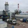 A large industrial factory complex in the city of Zaporizhzhia, Ukraine, with modern machinery and equipment. The scene should include workers in safety gear, heavy machinery, and industrial buildings. The atmosphere should convey a sense of industrial activity and economic significance.