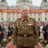 A dignified elderly veteran in a formal Soviet-era military uniform with medals, standing proudly in front of a historic Russian town hall building with red banners and flowers, surrounded by a small crowd of officials and well-wishers celebrating his 65th anniversary, soft natural lighting, detailed textures, respectful and solemn atmosphere